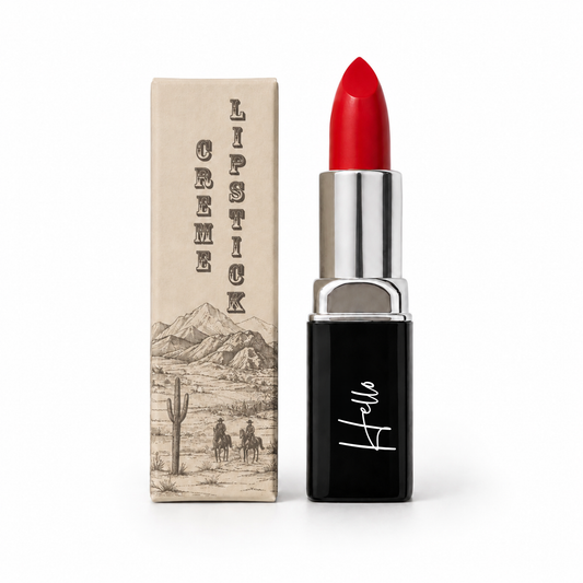 An open tube of Hello Biscuit Beauty Kiss This creme lipstick standing next to its custom box featuring a vintage western desert illustration of cowboys and a saguaro cactus on a white background