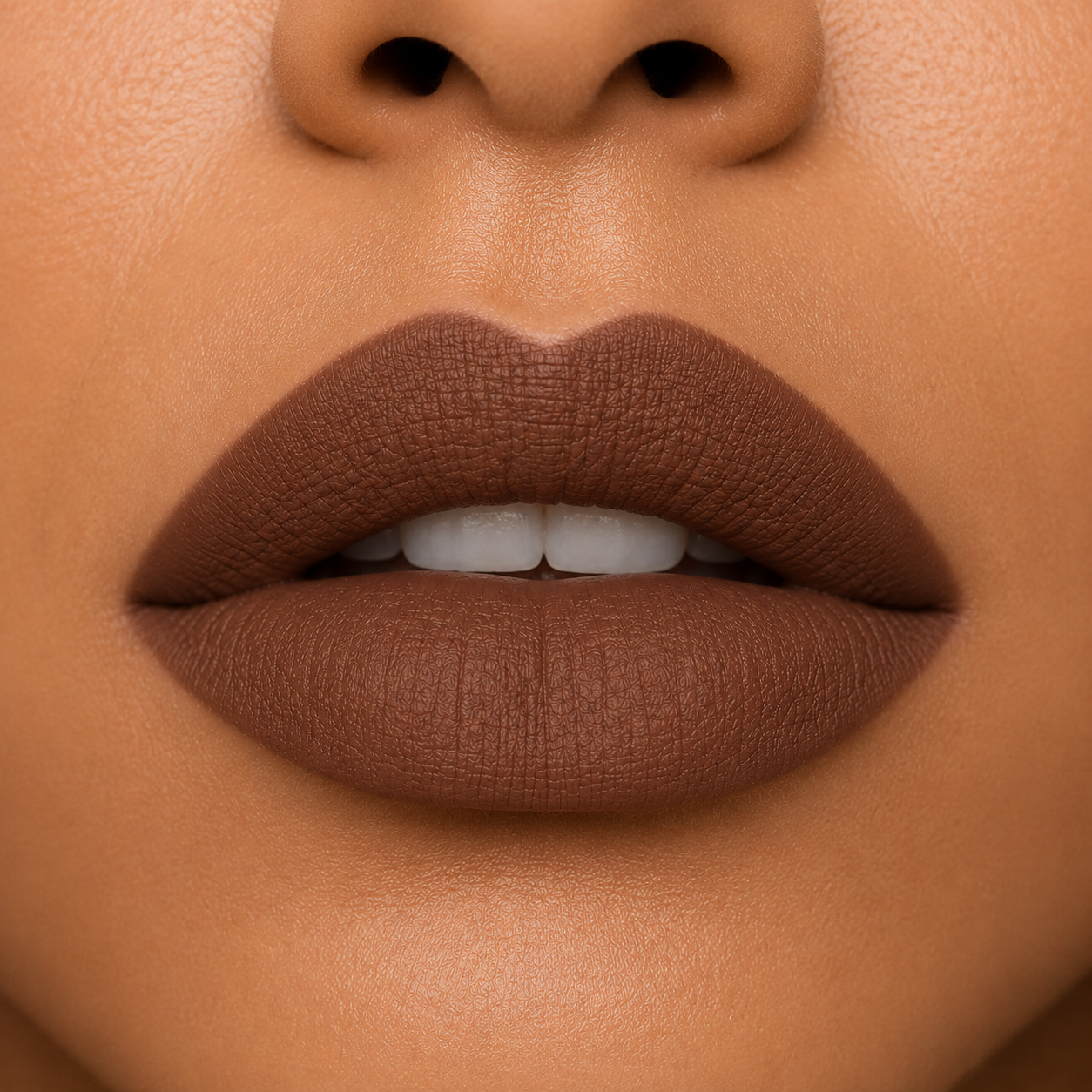 A close up view of a model's lips showcasing Hello Biscuit Beauty Backwoods matte lipstick, a deep muted mocha brown shade with a velvet matte finish.