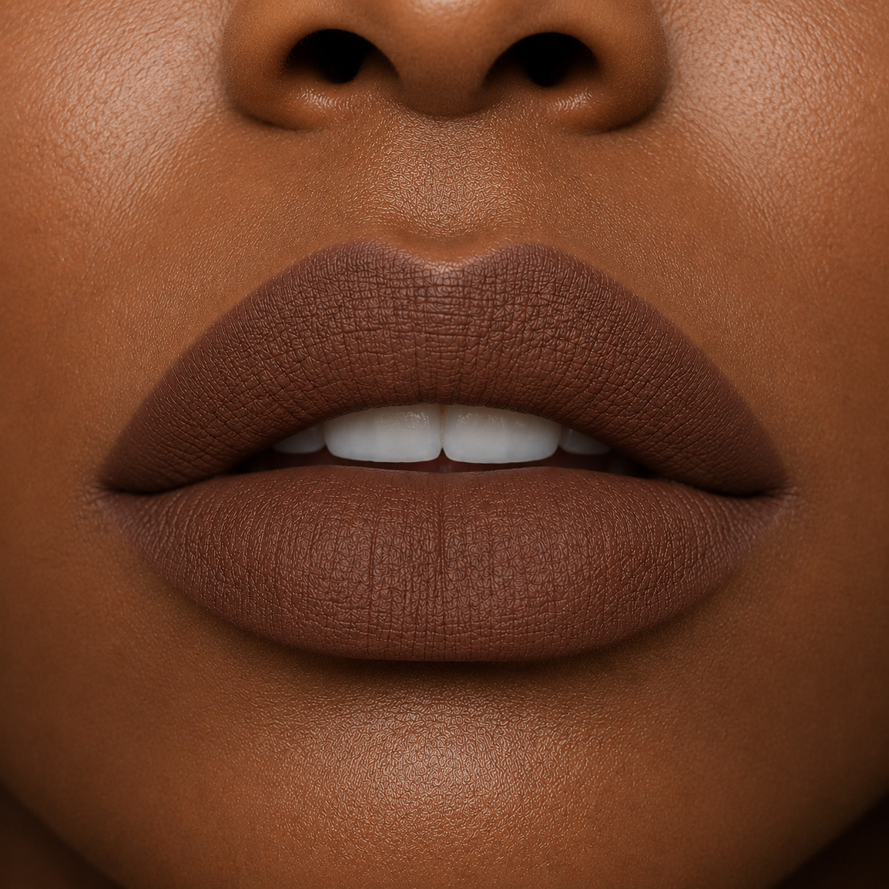A detailed close up view of full lips on a deep skin tone wearing Hello Biscuit Beauty Backwoods matte lipstick, a deep muted mocha brown shade with a velvet matte finish