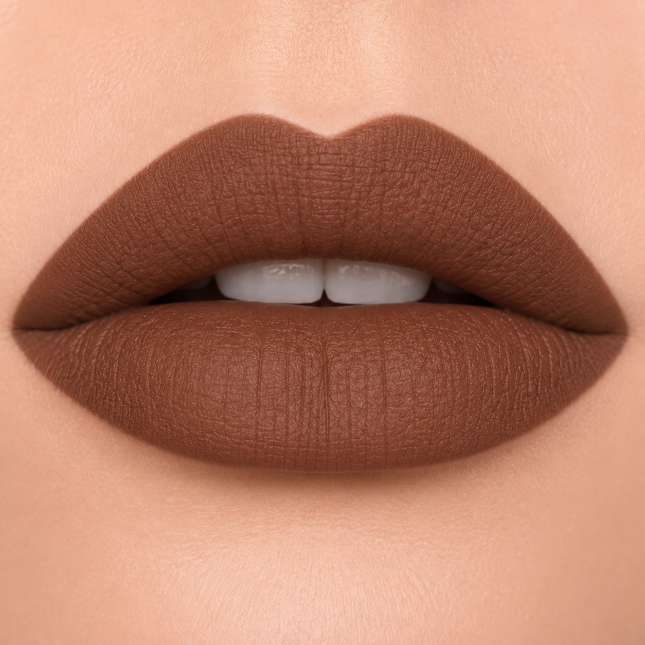 A detailed close up view of full lips wearing Hello Biscuit Beauty Backwoods matte lipstick, a deep muted mocha brown shade with a velvet matte finish