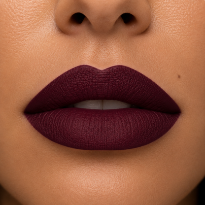 A detailed close up view of full lips on a warm skin tone wearing Hello Biscuit Beauty Jolene matte lipstick, a deep sparkling burgundy red wine shade with a smooth velvet matte finish