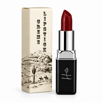 An open tube of Hello Biscuit Beauty Mamma Tried creme lipstick standing next to its custom box featuring a vintage western desert illustration of cowboys and a saguaro cactus on a white background