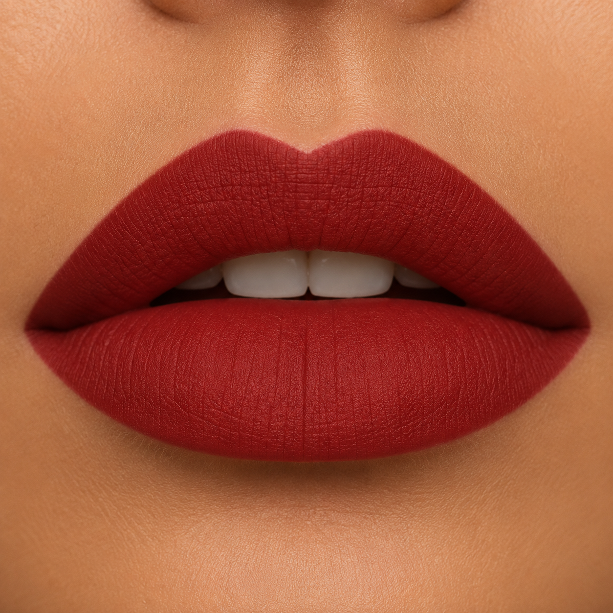 A detailed close up view of full lips on a warm skin tone wearing Hello Biscuit Beauty My Maria matte lipstick, a deep burnt red shade with a smooth velvet matte finish