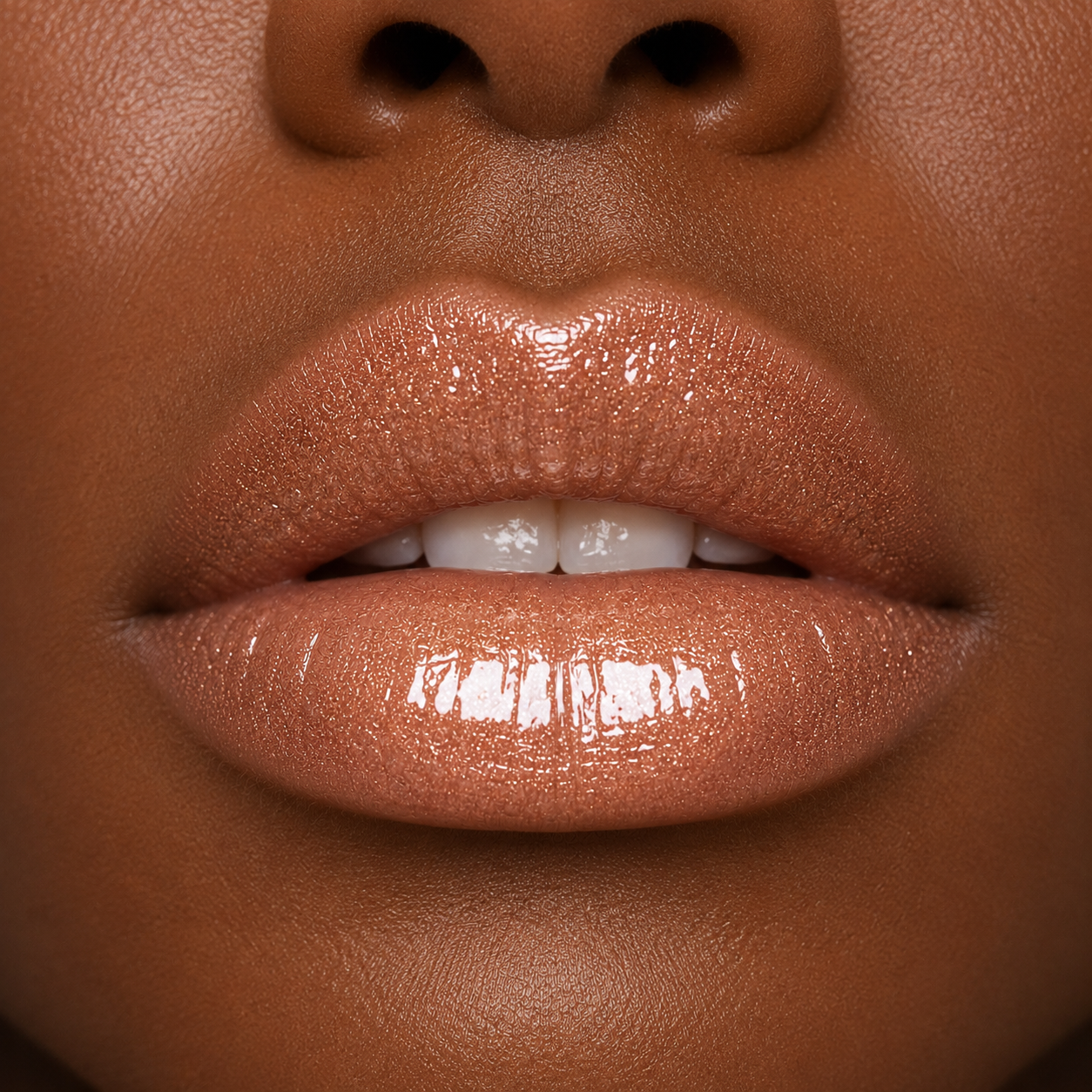 A detailed close up macro view of a model with a deep skin tone wearing the high shine Hello Biscuit Beauty Palomino Sparkly Mocha Lip Gloss showing a radiant pink shimmer