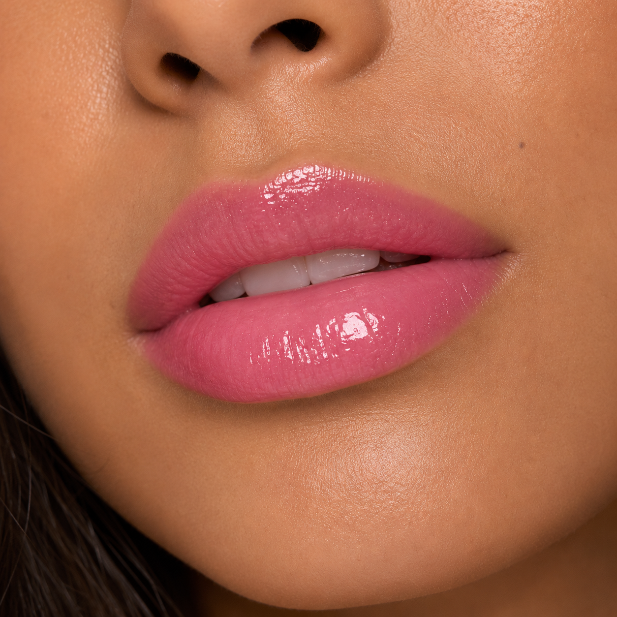 A detailed close up macro view of a model with a warm tan skin tone wearing the high shine Hello Biscuit Beauty Strawberry Wine Lip Gloss
