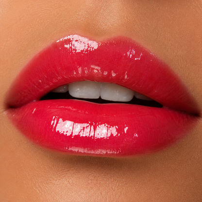 A detailed close up of full lips wearing Hello Biscuit Beauty Two Dozen Roses lip gloss, a vibrant true red shade with an ultra shiny glossy finish