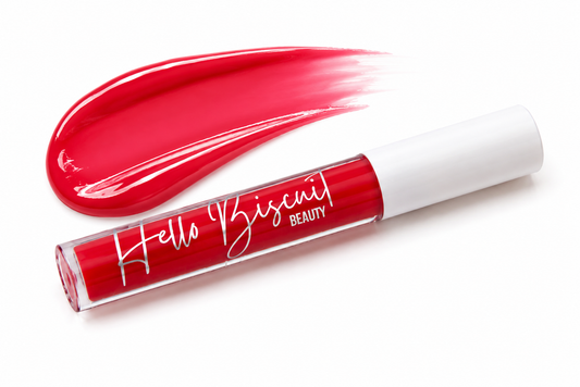 A tube of Hello Biscuit Beauty Two Dozen Roses lip gloss standing in front of a thick high shine swipe of the vibrant true red shade on a clean white background